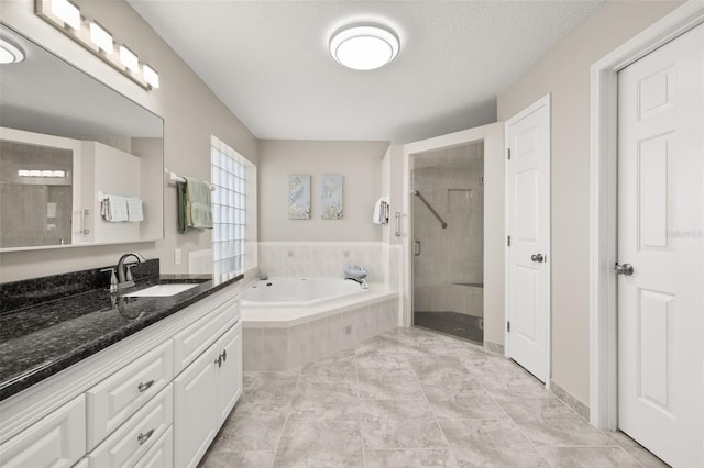 bathroom with a textured ceiling, vanity, and shower with separate bathtub