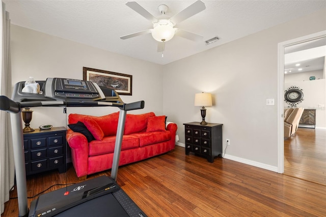 exercise room featuring ceiling fan, dark hardwood / wood-style floors, and a textured ceiling