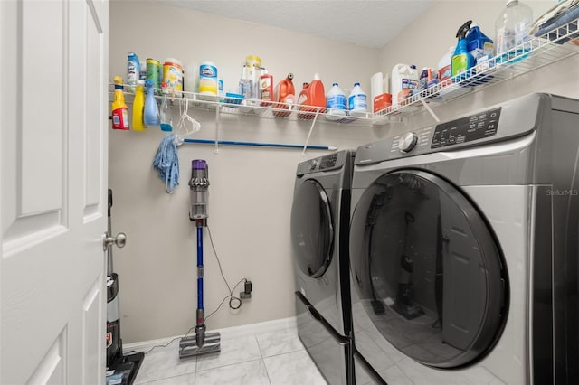 clothes washing area featuring washing machine and clothes dryer, light tile patterned floors, and a textured ceiling