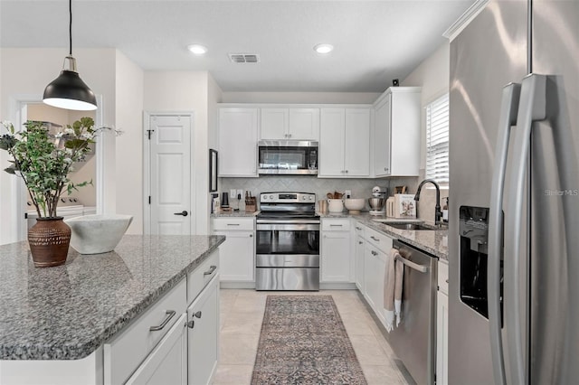 kitchen featuring decorative backsplash, a sink, pendant lighting, stainless steel appliances, and white cabinets