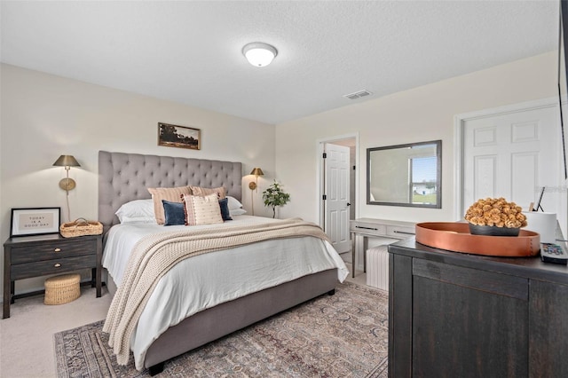 bedroom featuring carpet flooring, a textured ceiling, and visible vents