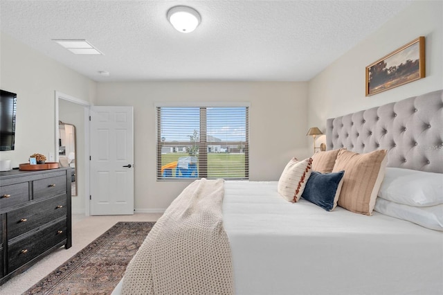 bedroom featuring light colored carpet, baseboards, and a textured ceiling