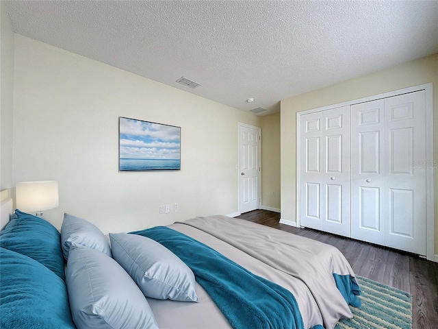 bedroom featuring baseboards, visible vents, dark wood-style flooring, a textured ceiling, and a closet