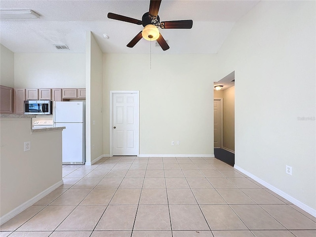 unfurnished room featuring light tile patterned floors, a towering ceiling, visible vents, and baseboards