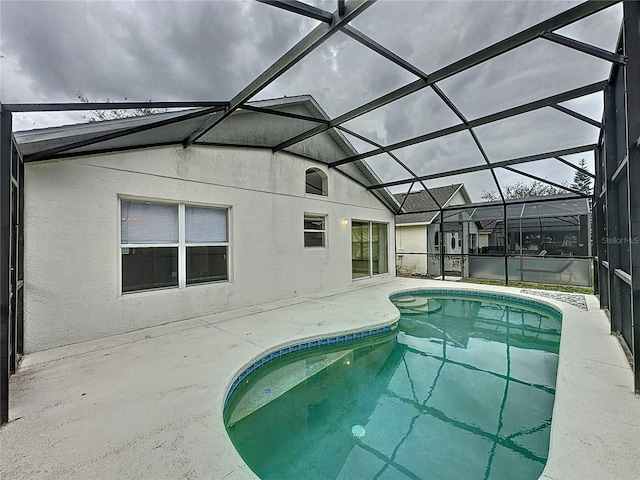 outdoor pool with glass enclosure and a patio