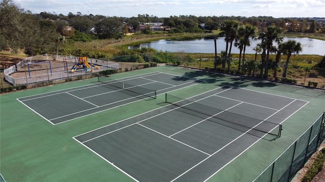 view of tennis court featuring playground community, a water view, and fence