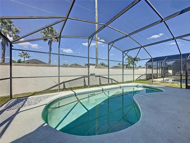 view of swimming pool featuring glass enclosure, a patio area, and a fenced in pool