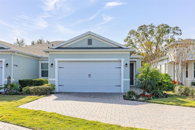 single story home featuring a garage, a front lawn, decorative driveway, and stucco siding