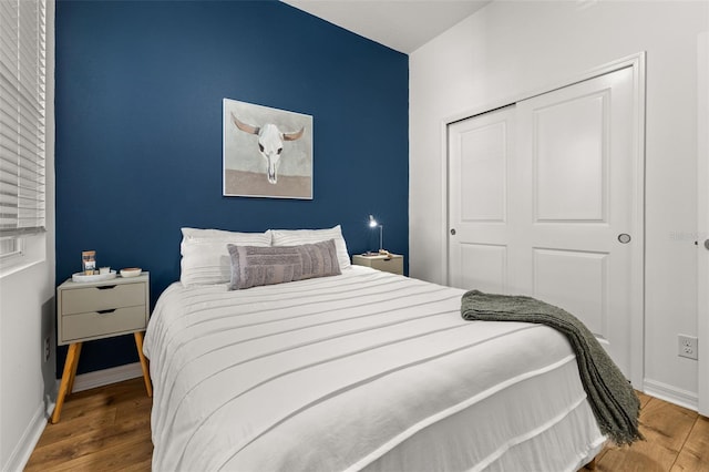 bedroom featuring a closet, wood finished floors, and baseboards