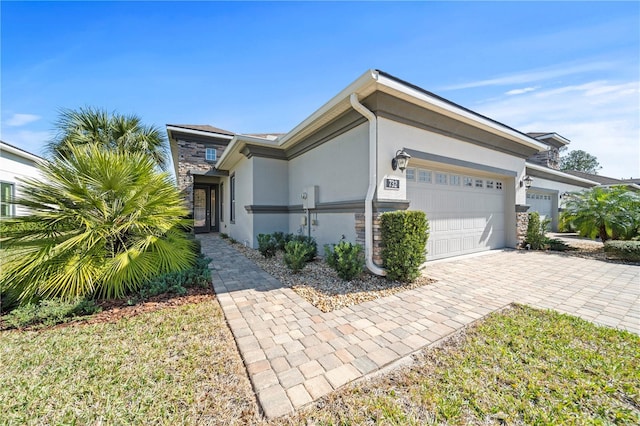 view of front of property with decorative driveway, stone siding, an attached garage, and stucco siding