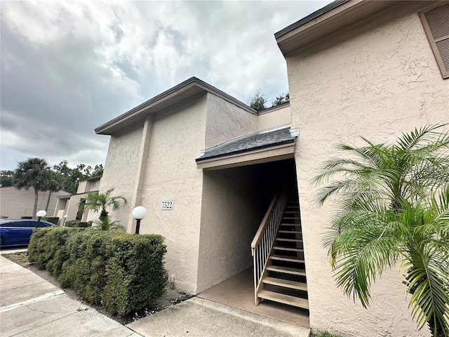 view of side of home featuring stairway and stucco siding