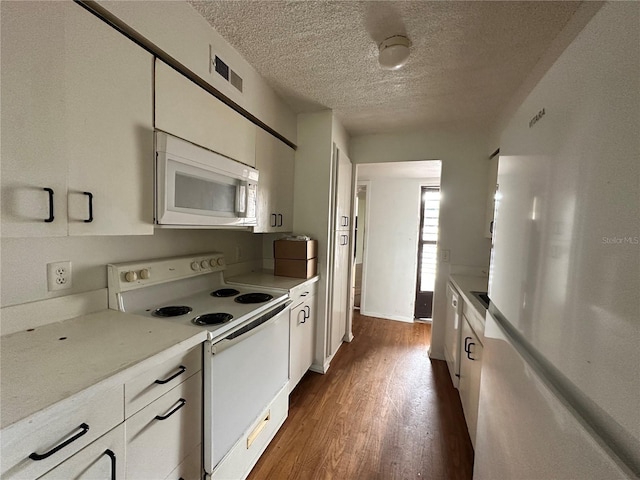 kitchen with dark wood finished floors, light countertops, visible vents, white cabinets, and white appliances