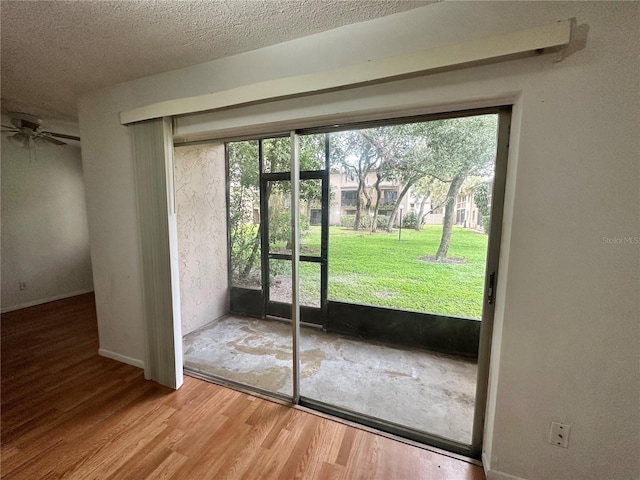 entryway with a ceiling fan, a healthy amount of sunlight, a textured ceiling, and wood finished floors