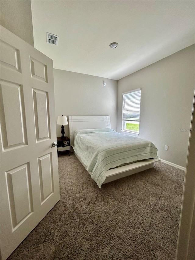 bedroom featuring visible vents, dark carpet, and baseboards