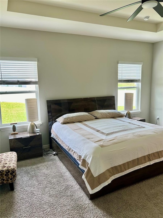 carpeted bedroom with a ceiling fan and multiple windows