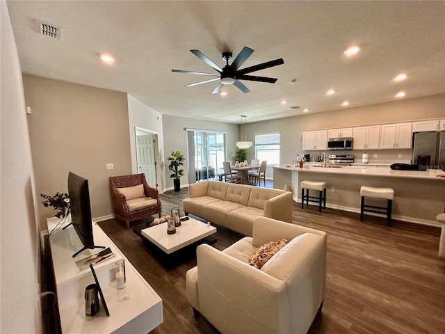 living room with dark wood-type flooring, recessed lighting, visible vents, and baseboards