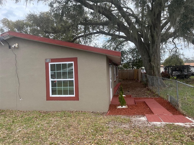 view of home's exterior with fence and stucco siding