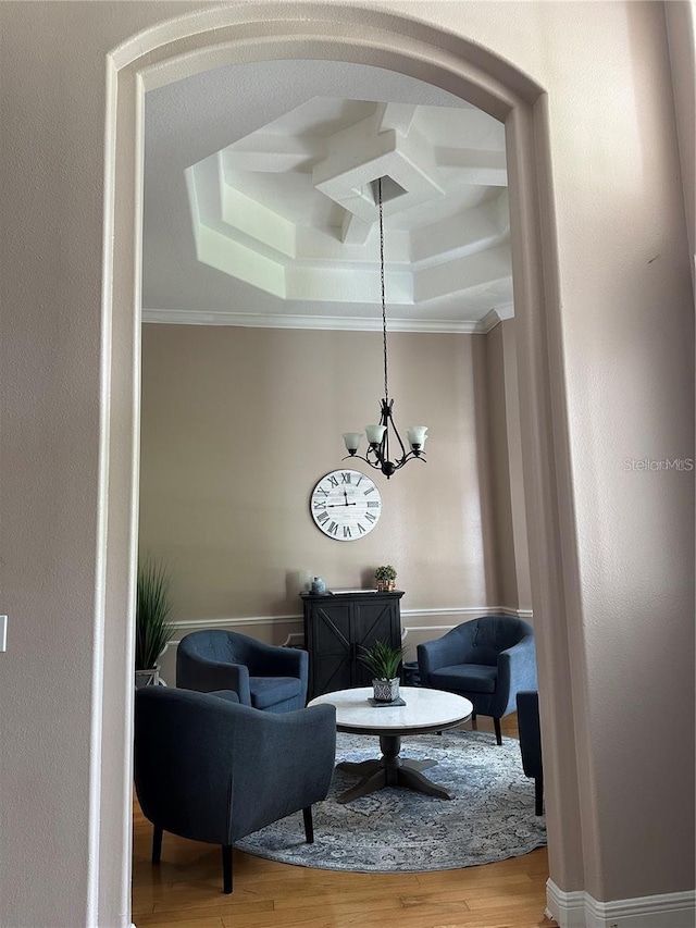 living room featuring coffered ceiling, hardwood / wood-style flooring, crown molding, and an inviting chandelier