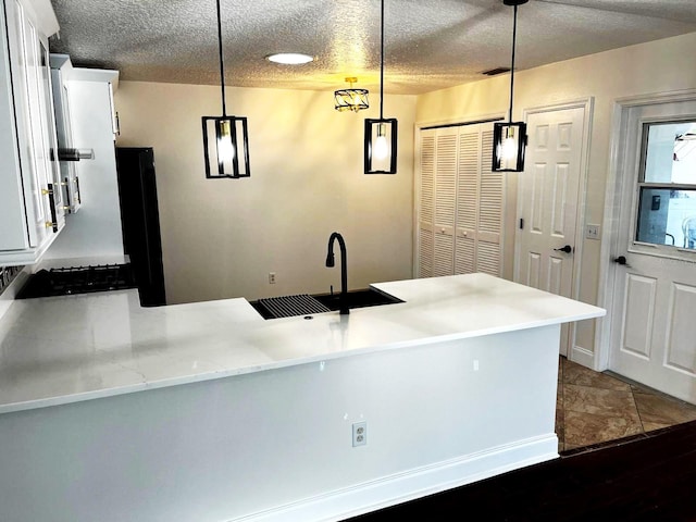 9319 SE 173rd Hyacinth St, The Villages, FL 32162 - kitchen with hanging light fixtures, a peninsula, white cabinetry, and a textured ceiling