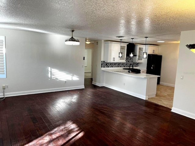 9319 SE 173rd Hyacinth St, The Villages, FL 32162 - kitchen with white cabinets, wood finished floors, a peninsula, light countertops, and pendant lighting