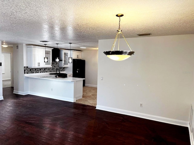 9319 SE 173rd Hyacinth St, The Villages, FL 32162 - kitchen with a peninsula, light countertops, white cabinetry, pendant lighting, and backsplash