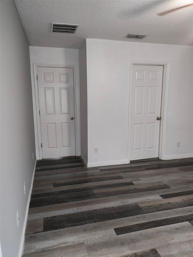 unfurnished room with visible vents, dark wood finished floors, and baseboards