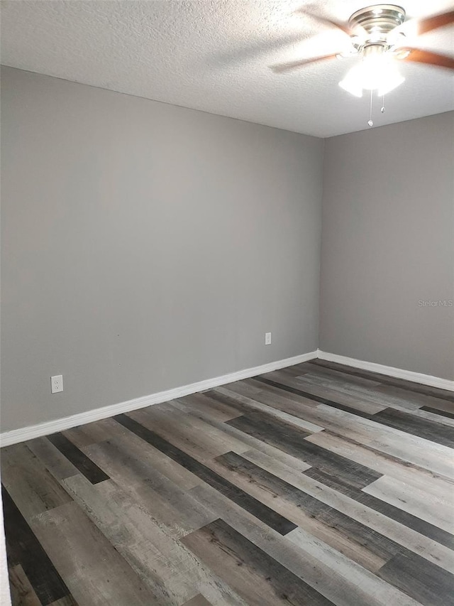 spare room with dark wood-style flooring, ceiling fan, a textured ceiling, and baseboards
