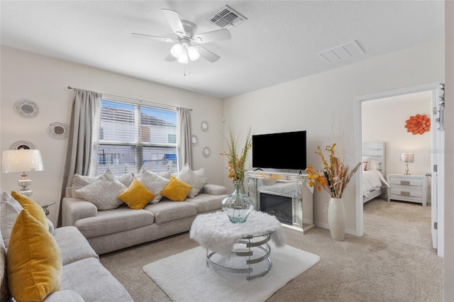 living room with light carpet, baseboards, visible vents, and a ceiling fan