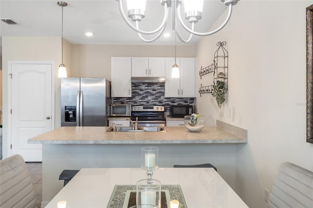 kitchen with stainless steel appliances, a breakfast bar, light countertops, and white cabinetry