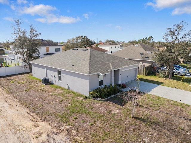 view of property exterior with central air condition unit, a garage, fence, driveway, and stucco siding