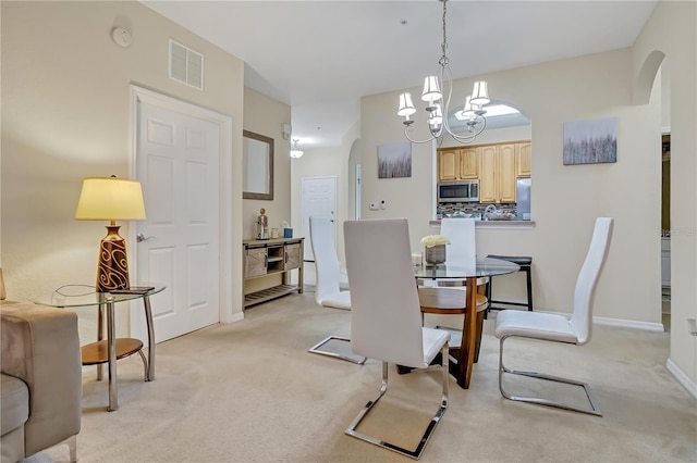 dining room with light carpet, visible vents, and arched walkways