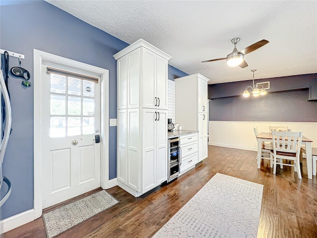 3004 Lake Margaret Dr, Orlando, FL 32806 - foyer entrance featuring wine cooler, ceiling fan, a chandelier, dark wood-style flooring, and a textured ceiling
