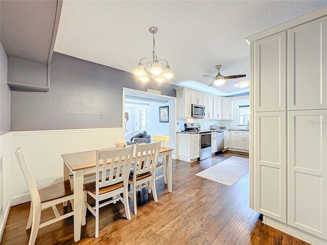 3004 Lake Margaret Dr, Orlando, FL 32806 - dining space featuring a textured ceiling, wainscoting, dark wood-type flooring, ceiling fan, and a chandelier