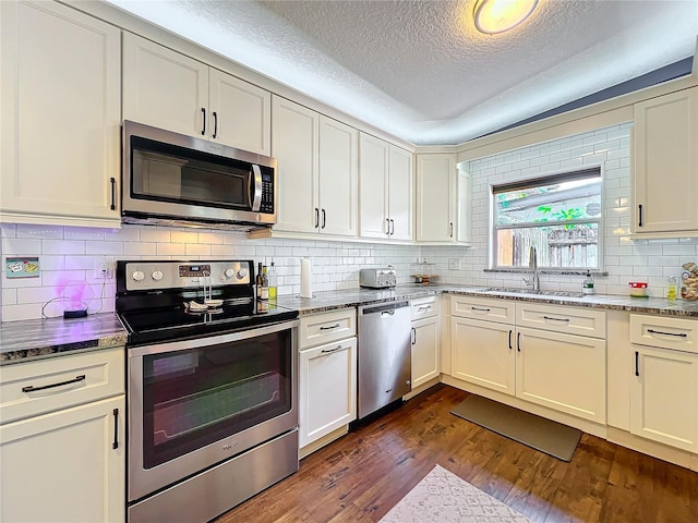3004 Lake Margaret Dr, Orlando, FL 32806 - kitchen with stainless steel appliances, a textured ceiling, dark wood-type flooring, tasteful backsplash, and stone counters