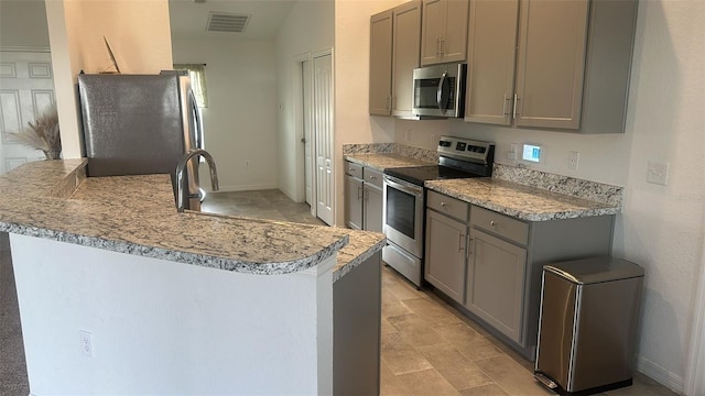 kitchen with gray cabinets, appliances with stainless steel finishes, sink, and kitchen peninsula