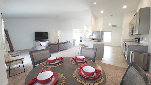 carpeted dining space with high vaulted ceiling