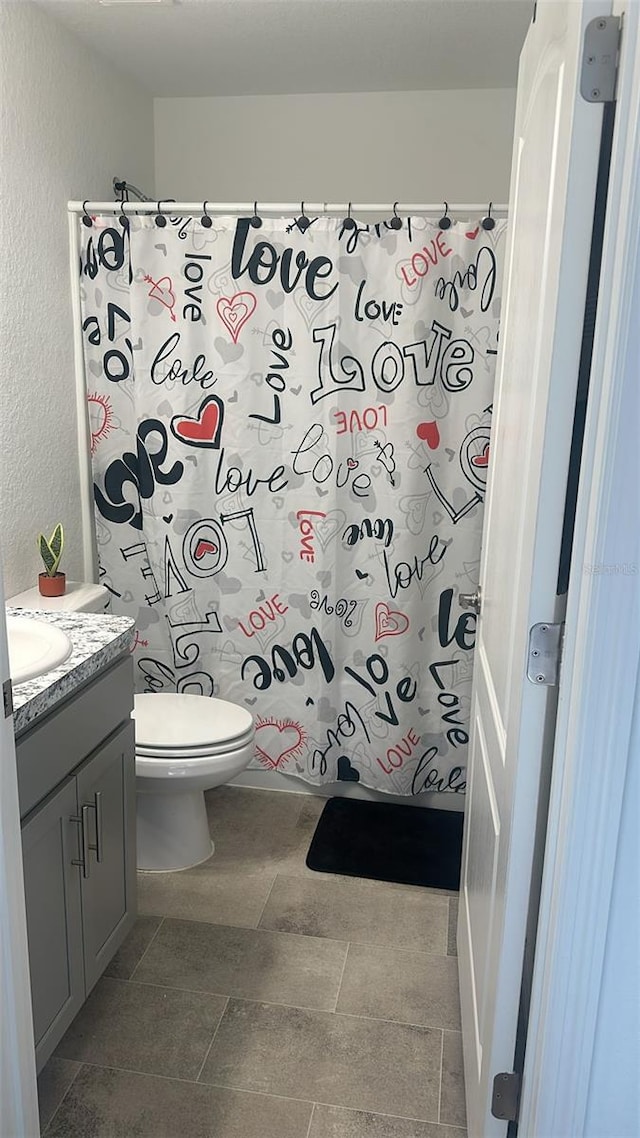 bathroom featuring curtained shower, vanity, and toilet