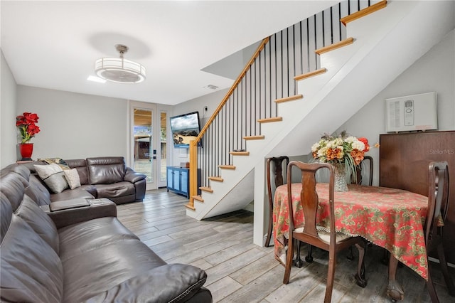 living room featuring light wood-type flooring, french doors, and stairs