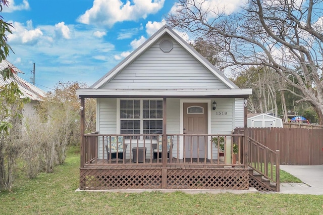 view of front of house with fence, a porch, and a front yard