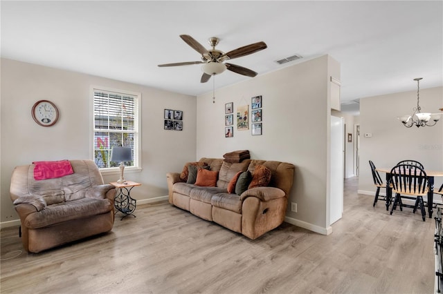 living area with visible vents, light wood-style flooring, baseboards, and ceiling fan with notable chandelier