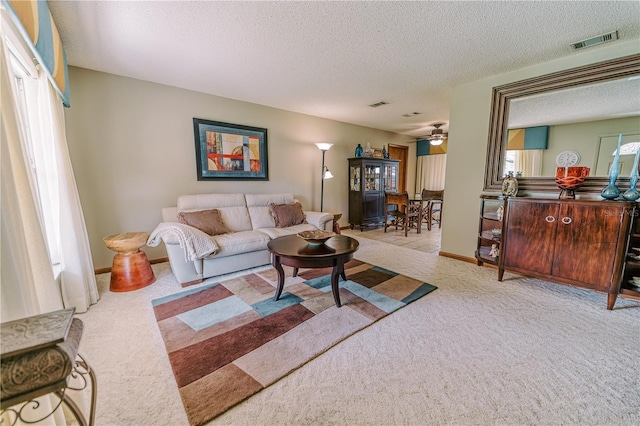 carpeted living room with a textured ceiling, ceiling fan, and a wealth of natural light