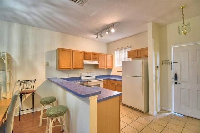 500 Monroe Cir, Davenport, FL 33896 - kitchen featuring dark countertops, white appliances, a breakfast bar area, a peninsula, and under cabinet range hood
