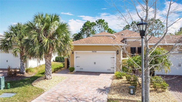 view of front facade with a garage, decorative driveway, roof with shingles, and stucco siding