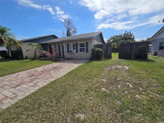 view of front facade featuring stucco siding, fence, cooling unit, and a front yard