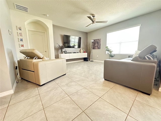 living room with ceiling fan, light tile patterned floors, and a textured ceiling