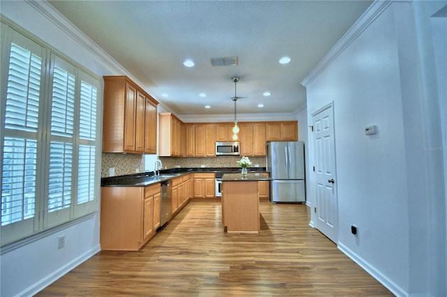 kitchen with a center island, decorative light fixtures, stainless steel appliances, dark countertops, and a sink