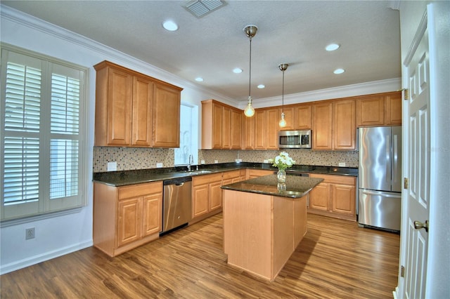 kitchen with a center island, decorative light fixtures, visible vents, appliances with stainless steel finishes, and a sink