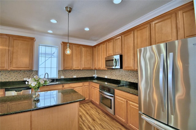 kitchen featuring dark stone counters, ornamental molding, hanging light fixtures, stainless steel appliances, and light wood-style floors