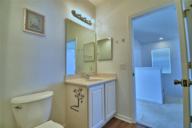 bathroom featuring toilet, baseboards, and vanity