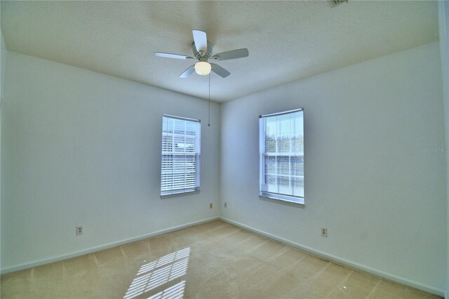 unfurnished room with a ceiling fan, light carpet, a textured ceiling, and baseboards